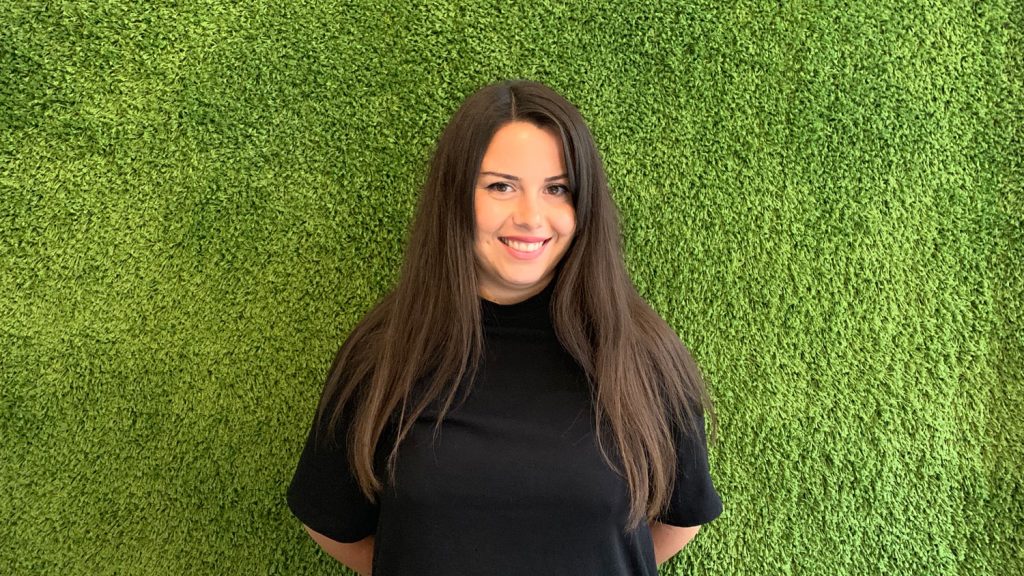 Utvecklare Elif Ali ler mot kameran mot en grön bakgrund
